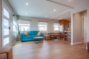 a living room with a blue couch and a kitchen at Ocean Beach Retreat, 3BR Newly Remodeled, Steps to Beach and Boardwalk in San Diego