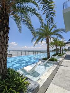 einen Pool mit Palmen und dem Meer in der Unterkunft River Panorama 2 Bedroom River View in Ho-Chi-Minh-Stadt