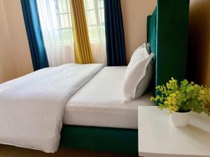 a bed with a green headboard next to a window at Two bedroom Paradise Apartment Embu in Embu