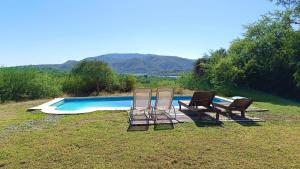 3 chaises assises à côté d'une piscine dans l'établissement El Cardon - Casa de Campo, à Coronel Moldes