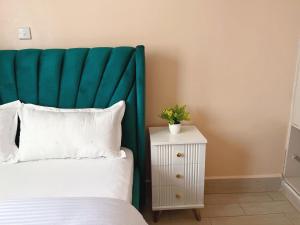 a bed with a green headboard next to a night stand at Two bedroom Paradise Apartment Embu in Embu