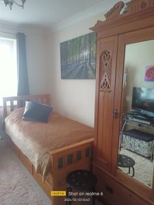 een slaapkamer met een bed en een kast met een televisie bij Goldy's place in E17 Room2 in Londen