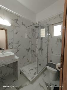 een badkamer met een douche, een toilet en een wastafel bij Votsalo Studios & Apartment in Frangokastello