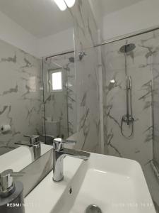 y baño con lavabo, ducha y espejo. en Votsalo Studios & Apartment, en Frangokastello