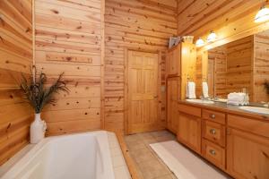 La salle de bains est pourvue d'une cabine en rondins, d'une baignoire et d'un lavabo. dans l'établissement Our Get Aweigh - Cabin Retreat - private hot tub - community pool - Goshorn Lake Access, à Saugatuck 27 autres photos