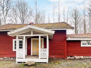 una casa rossa con un portico bianco e una porta gialla di 5 person holiday home in ÅSEDA a Åseda