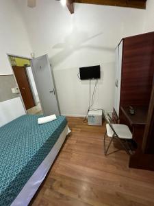 um quarto com uma cama, uma televisão e uma cadeira em Arguibel 2833 em Buenos Aires