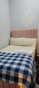 a bed with a blue and white checkered blanket on it at MAMA DELIGHT GUEST ROOM in Abu Dhabi