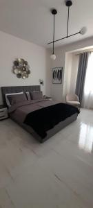a bedroom with a large bed and a chair at Coral Reef Apartments in St Paul's Bay