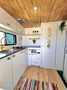 uma cozinha com armários brancos e um tecto de madeira em Camper estatico solo para alojar en el frente del Mar em La Tejita