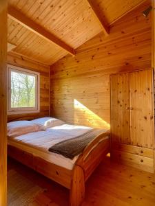- une chambre avec un lit dans une cabane en bois dans l'établissement Projekt Stajnia - Nadmorski Ośrodek Jazdy Konnej - noclegi, à Łazy