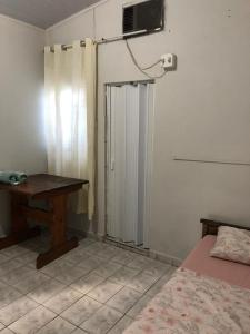 a bedroom with a bed and a table and a window at Hostel Dourado in Barra do Garças