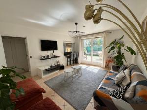 a living room with a couch and a tv at Le jardin du stade by UTA HOUSE in Saint-Denis