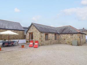 a stone house with red chairs and a patio at Riviere Barton in Hayle