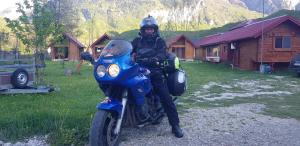 Um homem está sentado numa moto azul em PROKLETIJE eko katun Vusanje em Gusinje