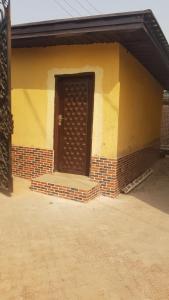 un edificio amarillo con una puerta marrón en él en Edo Home en Benin City