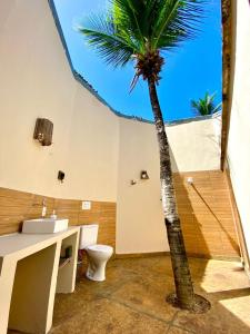 a bathroom with a palm tree and a toilet at Pousada Velho Bateau in Atins