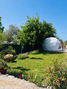 Tienda blanca con cúpula en un jardín con flores en Sougia Glamping, en La Canea