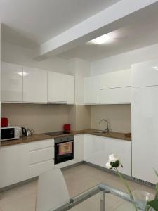 uma cozinha com armários brancos e uma mesa de vidro em Pool and spa apartment 1BR em Donji Morinj