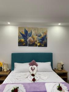 a bedroom with a bed with three paintings on the wall at Apartmani Pranić in Mostar