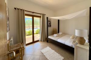 une chambre avec un lit et une grande fenêtre dans l'établissement Traumhafte Finca am Es Trenc, à Ses Covetes