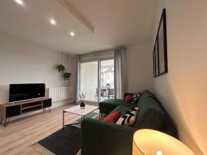 a living room with a green couch and a television at T2 cosy avec parking in Annemasse