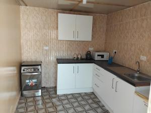 a small kitchen with white cabinets and a sink at Mariama's Apartment in Brufut