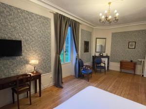 a room with a bed and a desk and a tv at Château De La Coutancière in Brain-sur-Allonnes