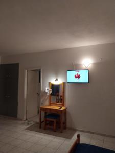 Habitación con escritorio y TV en la pared. en Creta Sun Hotel Studios en Agia Pelagia