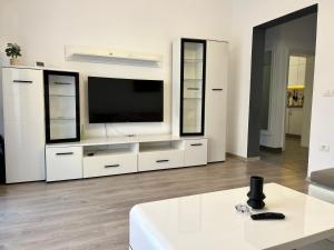 a living room with a large white entertainment center with a television at Nathallie Cosy Apartment in Timişoara