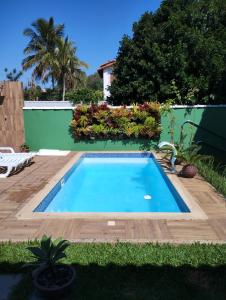 a swimming pool in a yard with a wooden deck at Flats Casa Verde in Saquarema