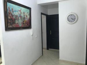 a clock on a wall next to a room with a painting at Appartement Familial Proche Aeroport Bab Andalous Tanger in Tangier