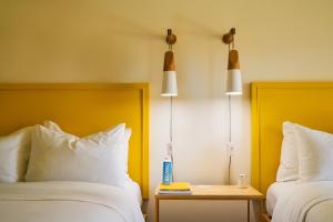 a hotel room with two beds and a table and two lamps at The Saguaro Palm Springs in Palm Springs