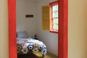 Chalé na floresta com frigobar في أورو بريتو: غرفة نوم بسرير في مدخل احمر