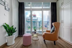 a living room with a chair and a large window at The Rixx Ben Thanh Tower - The One Saigon in Ho Chi Minh City
