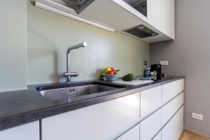 a kitchen with a sink and a bowl of fruit on the counter at SUITE Home Ladispoli in Ladispoli