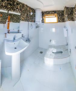 La salle de bains blanche est pourvue d'un lavabo et de toilettes. dans l'établissement Royal Brangsa Guest House, à Skardu