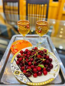 - une assiette de fruits sur un plateau avec deux verres à vin dans l'établissement Royal Brangsa Guest House, à Skardu