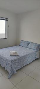 a bedroom with a bed with a blue blanket and a window at Casa aconchegante in Guanamby