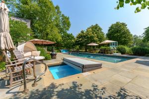 a swimming pool with two chairs and an umbrella at Private Pool & Lake MI access, hot tub, putting green, basketball court, and more! in Fennville
