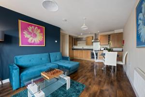 a living room with a blue couch and a kitchen at High Wycombe Short Stay Apartment in High Wycombe