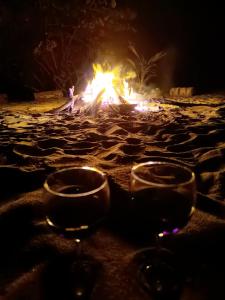 two wine glasses sitting on a beach with a fire at Sierra Sagrada Tayrona in Guachaca