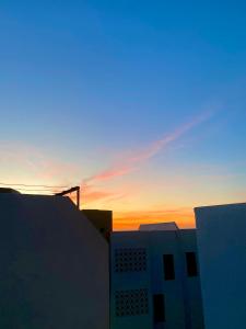 un coucher de soleil sur les toits des bâtiments au coucher du soleil dans l'établissement la casa bella 5 minutes de la plage, à Essaouira