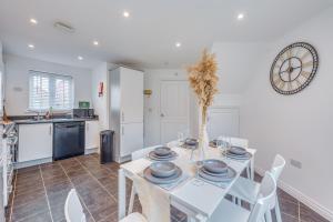 a dining room with a table and chairs and a clock at Oakbridge House - 6 mins drive to CMK - Free Parking, Fast WiFi, Smart TVs with Sky and Netflix by Yoko Property in Milton Keynes