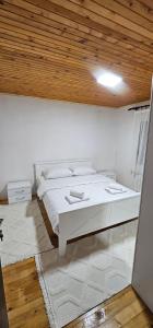een wit bed in een kamer met een houten plafond bij Apartmani KASALICA in Žabljak