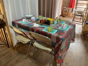 ein Tisch mit Stühlen und ein Tischtuch mit Geschirr darauf in der Unterkunft Le Refuge Familial in Fondamente
