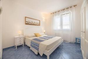 a white bedroom with a bed and a window at Belvedere Apartments A in Marina di Mancaversa