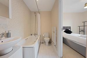 a bathroom with a sink and a toilet and a bed at High Wycombe Short Stay Apartment in High Wycombe