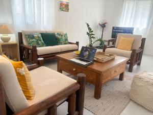 a living room with couches and a laptop on a coffee table at Oasis de Paix près de la plage in Flic-en-Flac