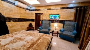 a bedroom with two chairs and a bed and a tv at B&B Apartment & Hotels in Lahore
